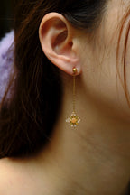 Close-up of a person wearing a gold earring with a star-shaped pendant.