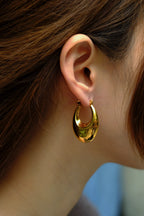 Gold hoop earring worn by a person with brown hair.