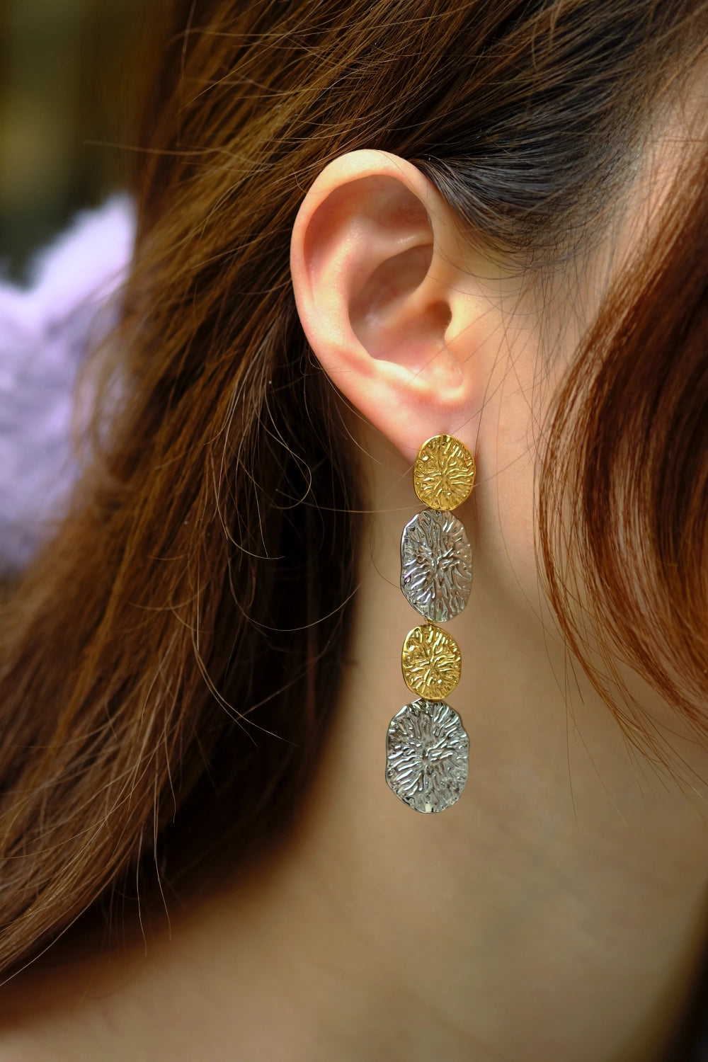 Close-up of a person wearing gold and silver circular earrings.