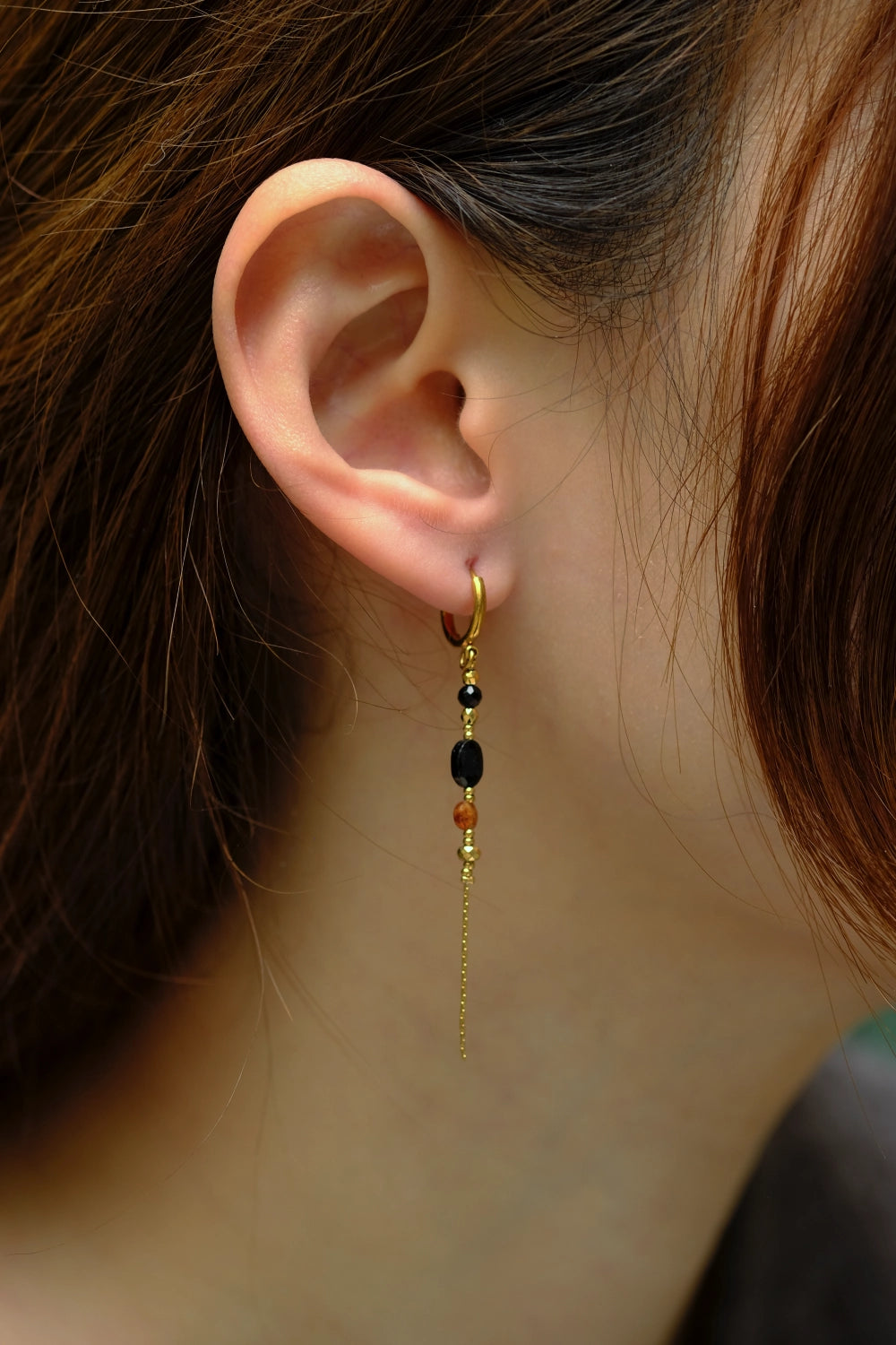 Close-up of an ear with a dangling earring featuring beads.