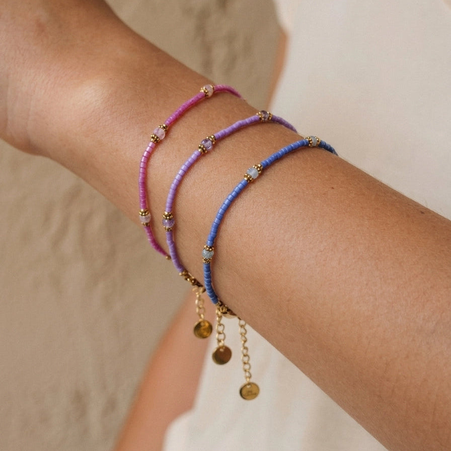 Two colorful beaded bracelets on a wrist against a neutral background